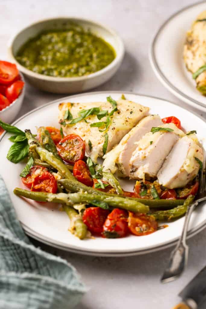 Baked chiken pesto with green beans and tomatoes served on a plate