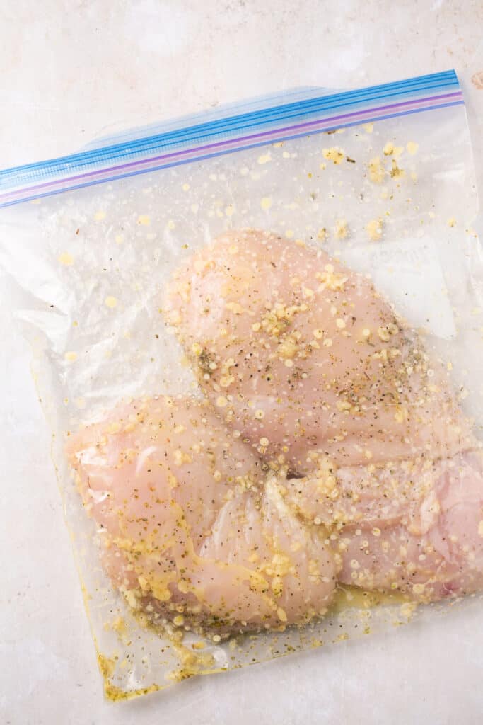 Raw chicken with marinade in a zip lock bag.