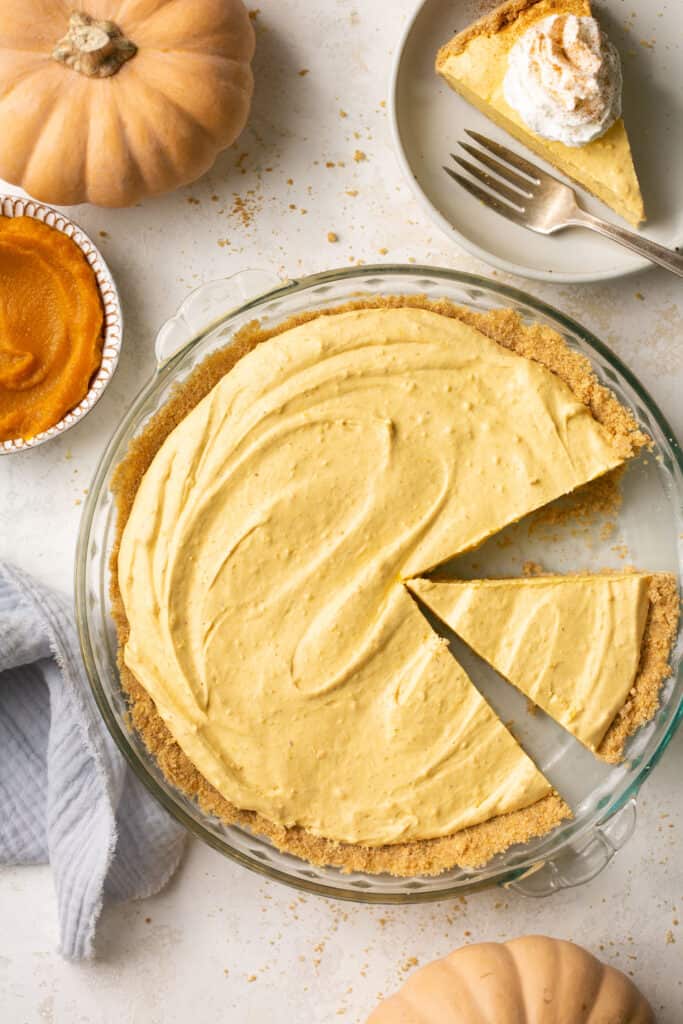 No bake pumpkin dessert pie in a pie dish, part of it cut into a slice.