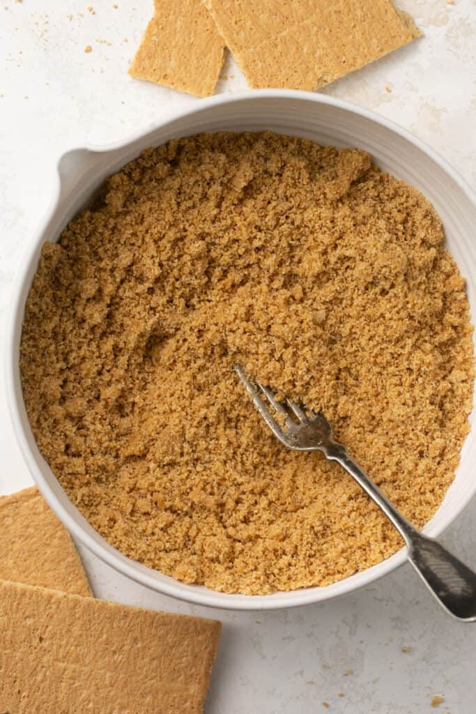 Graham cracker crumbs in a mixing bowl with a fork.