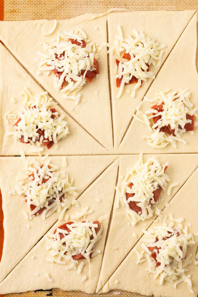 Pepperoni, sauce, and cheese added to each triangle.