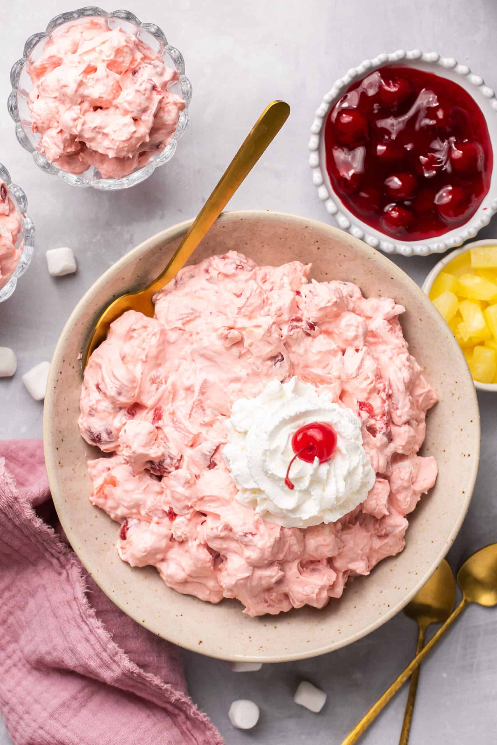 Cherry Pie Fluff topped with whipped cream and a cherry in a bowl with a spoon.