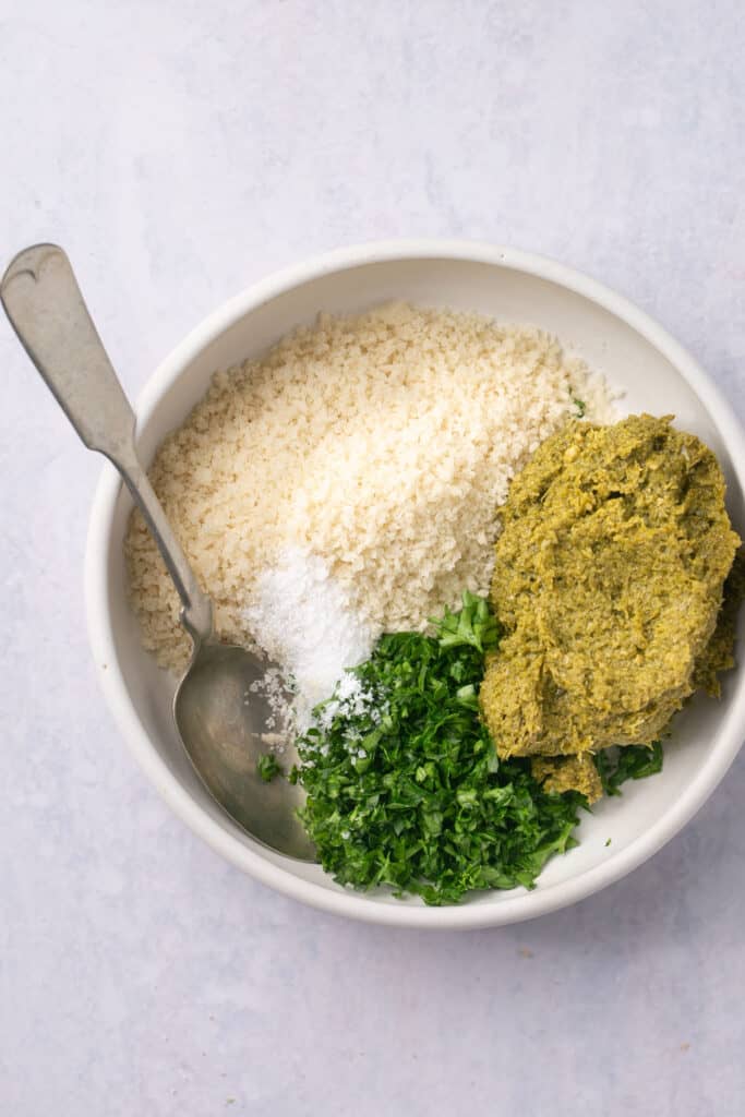 Pesto ingredients in a small bowl with a spoon.