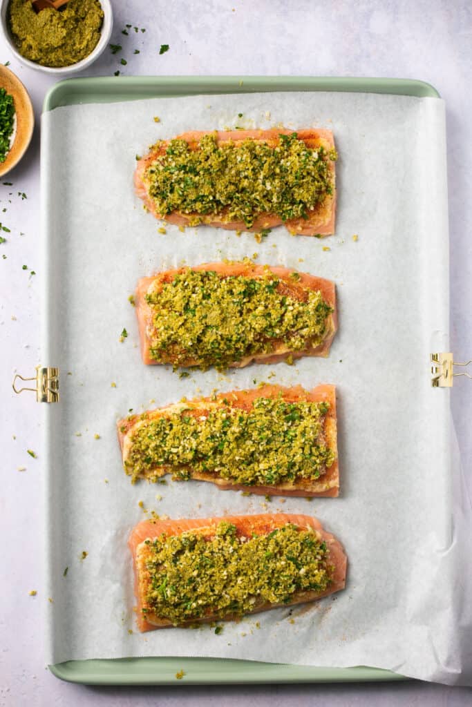 Raw salmon topped with brown sugar mixture in a baking sheet with parchment paper.