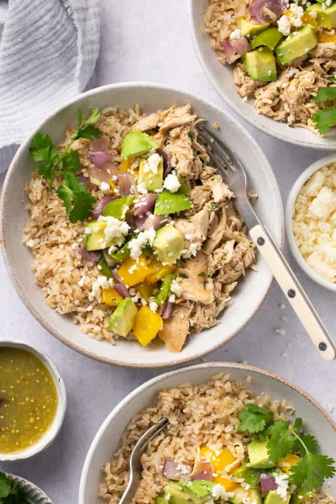 Salsa verde chicken topped with peppers and onions served in bowls  with forks