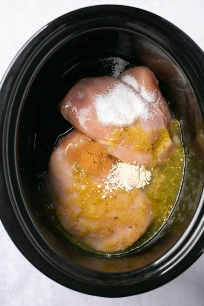 Ingredients for salsa verde chicken bowls in a slow cooker before being cooked.