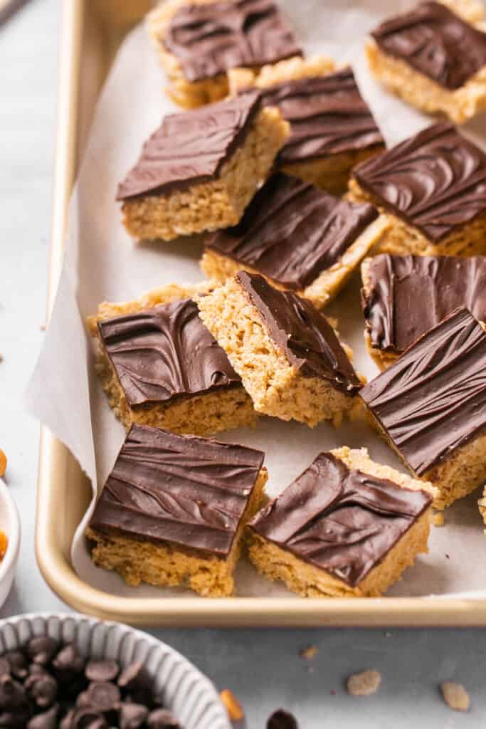 Healthy scotcheroos cut into bars on a baking sheet with parchment paper.