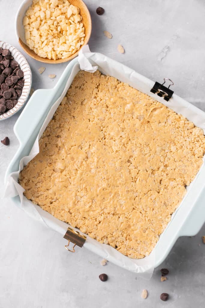 Cereal mixture pressed into a square baking dish.