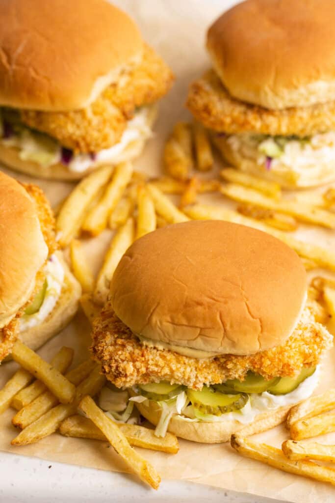 Zoomed in view of Air Fryer Chicken Sanwiches with french fries on parchment paper.