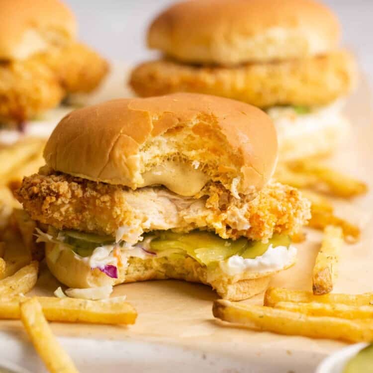 Air fryer chicken sandwiches with french fries on parchment paper.