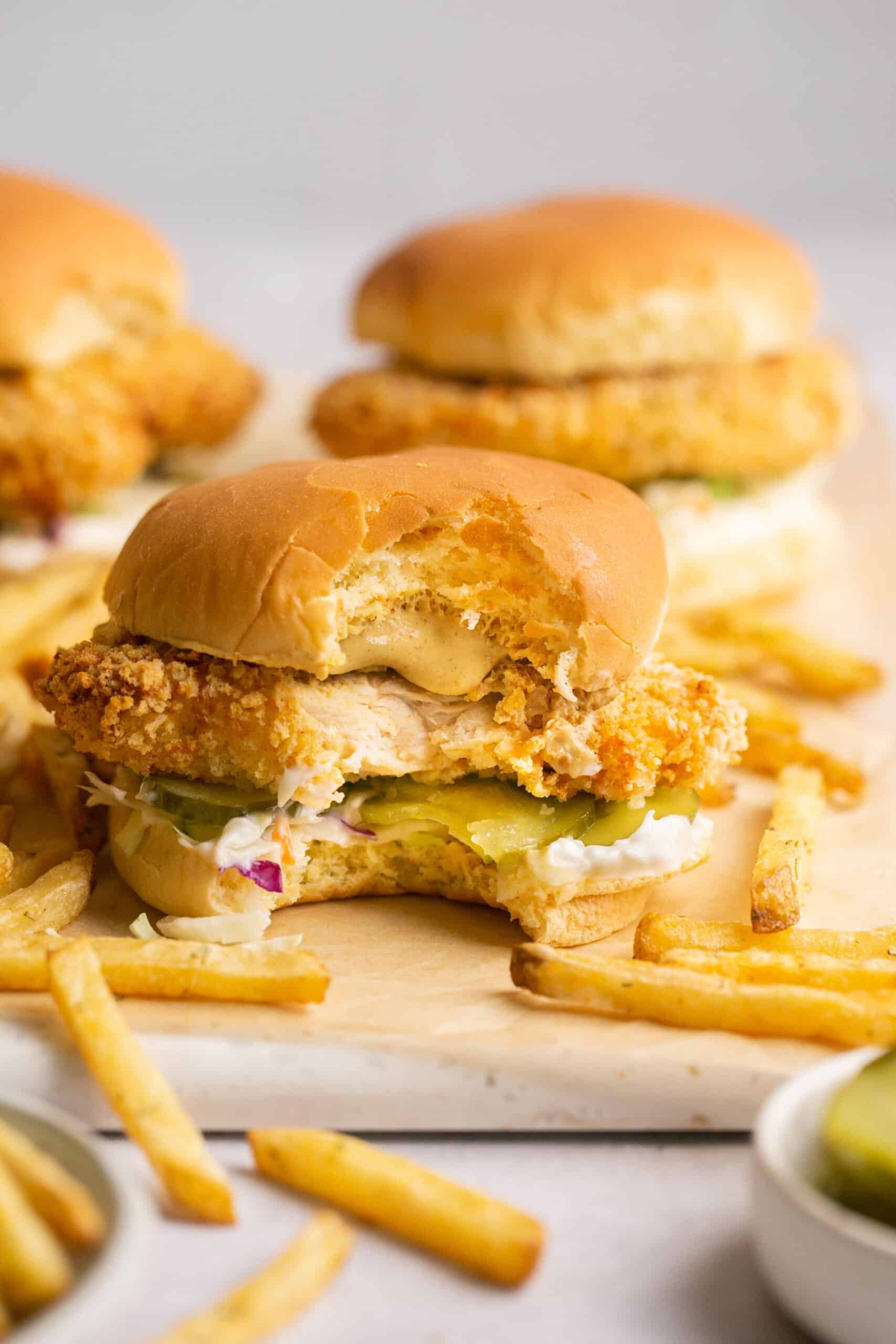 Air fryer chicken sandwiches with french fries on parchment paper.