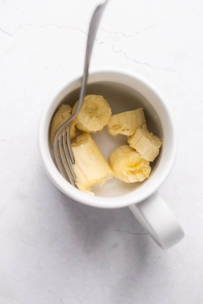Banana slices in a mug with a fork.
