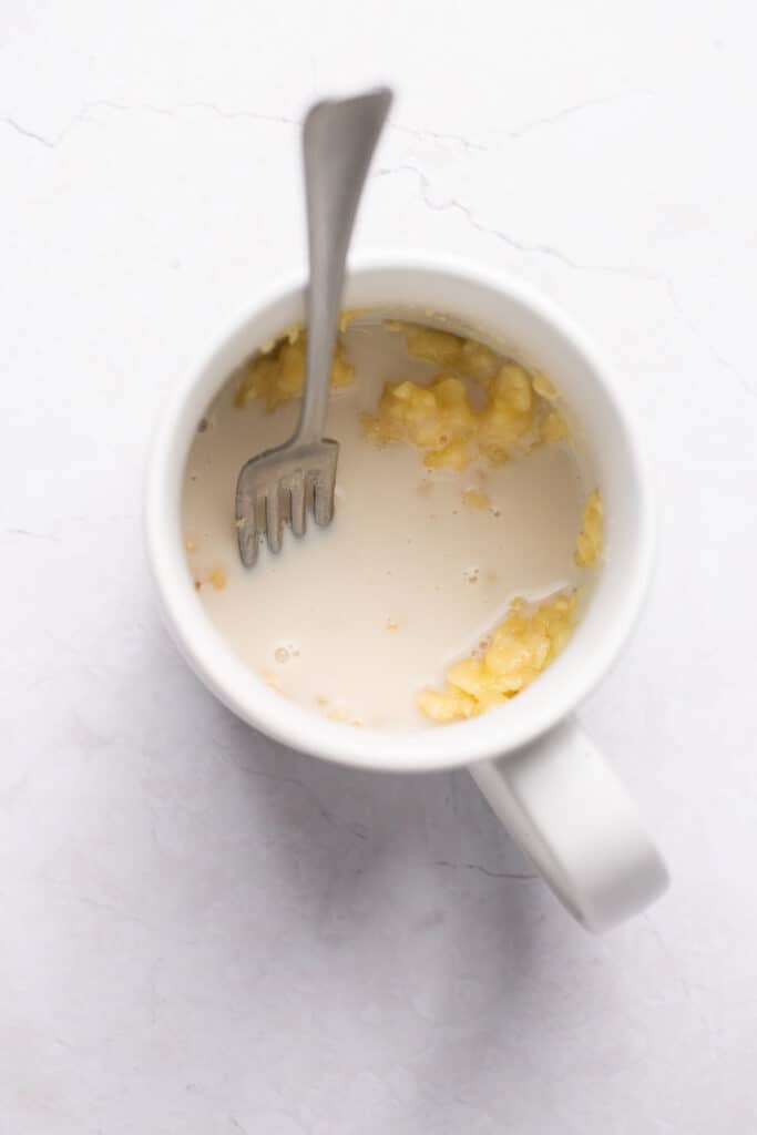 Milk and mashed banana in a mug with a fork.