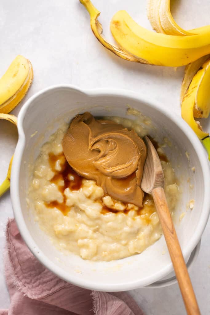 Peanut butter and mashed banana in a mixing bowl before being mixed together.