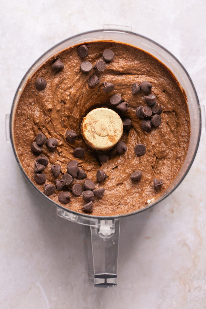Ingredients blended together in a food processor with chocolate chips being added in.