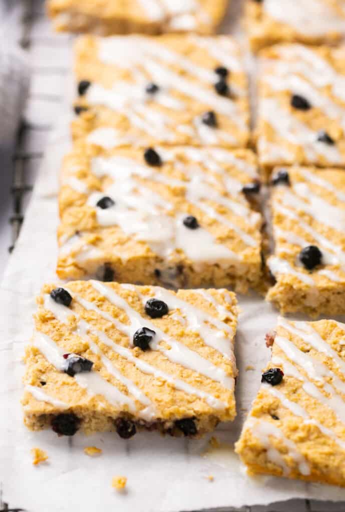 Bo berry bars topped with icing on parchment paper.