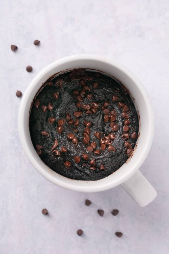 Chocolate protein lava cake in a mug topped with chocolate chips.