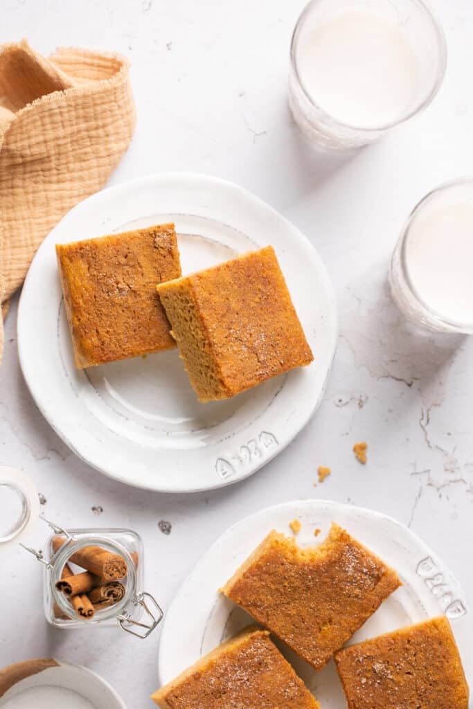 Two cinnamon sugar protein cake bars on a small plate with a glasses of milk on the side.