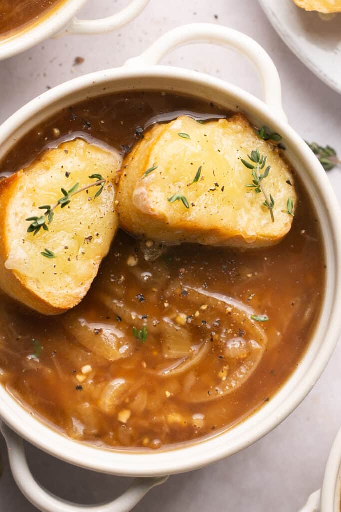 Close up view of healthy french onion soup recioe topped with cheesy baguette in a bowl