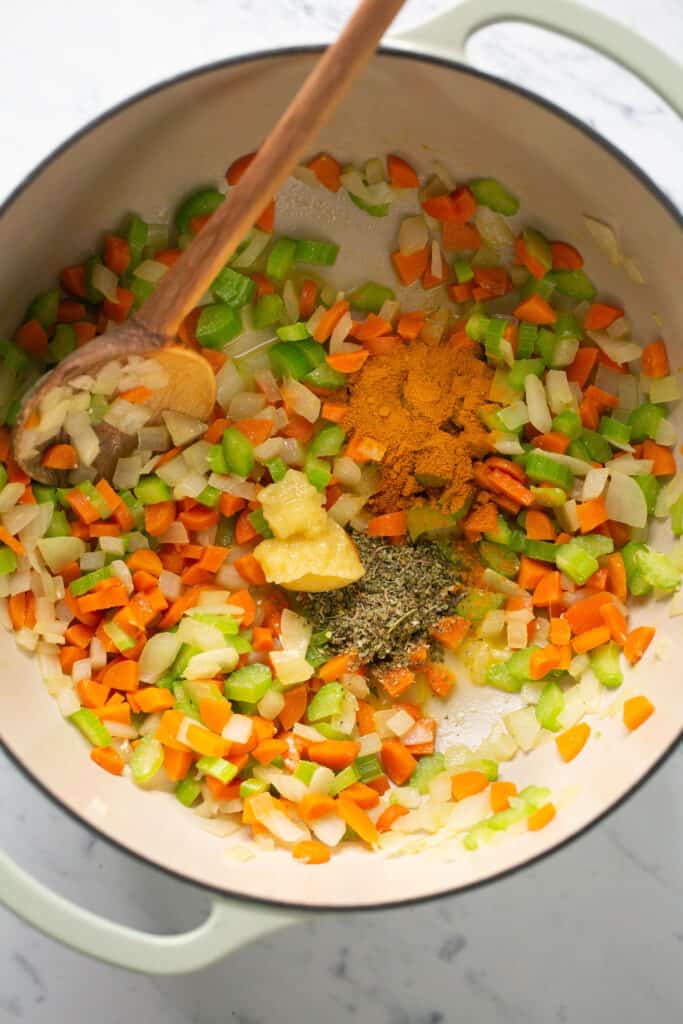Seasonings being added to the chopped veggies in the dutch oven.