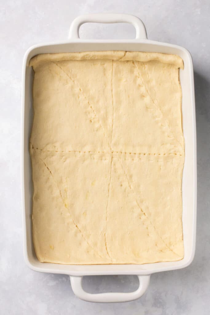 Crescent roll dough pressed into a rectangle baking dish.