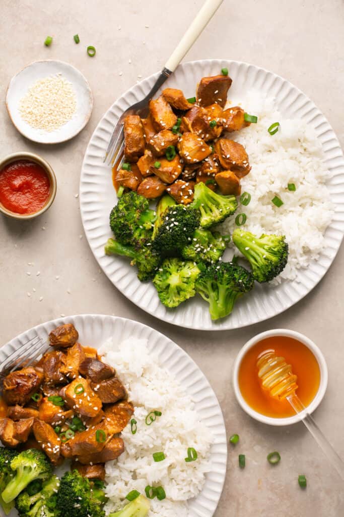 Honey sriracha chicken with rice and broccoli on plates with a forks