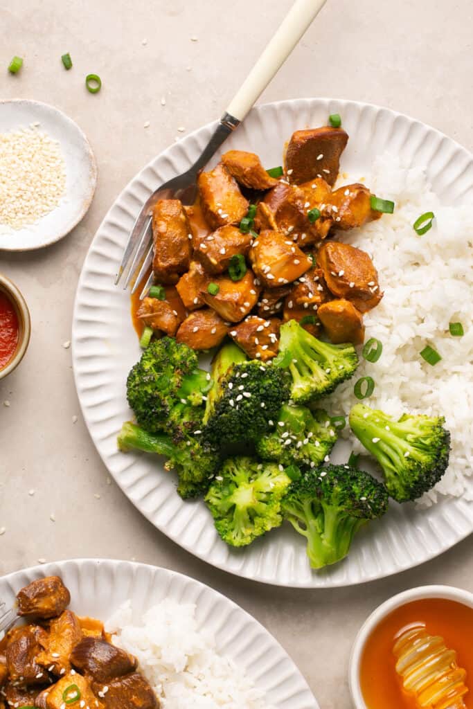 Honey sriracha chicken with rice and broccoli on a plate with a fork