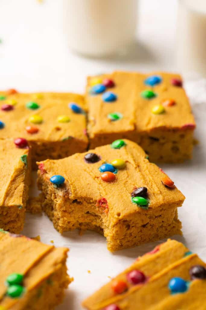 Zoomed in view of Soft Baked M&M Pumpkin Protein Oat Bars on parchment paper.