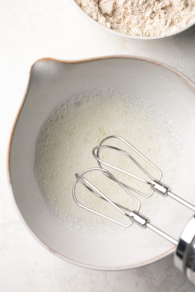 An electric hand mixer beating egg whites.