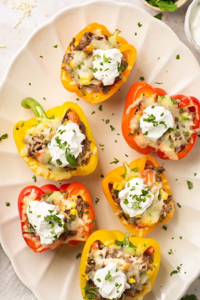 Healthy stuffed peppers with ground beef topped with sour cream on a serving platter