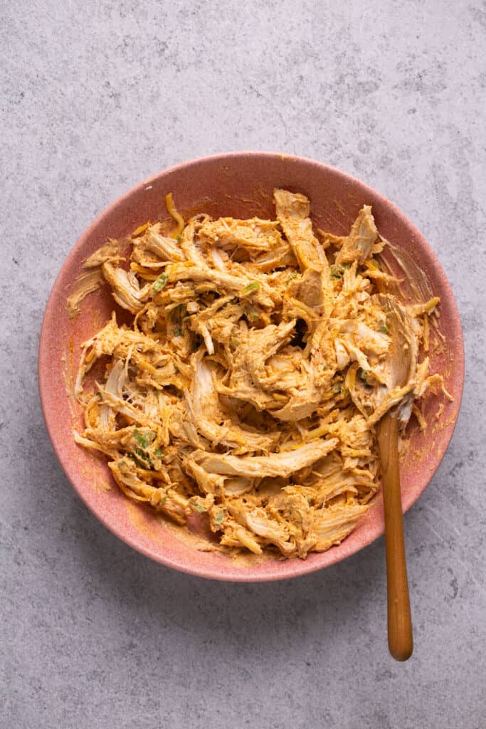 Cooked shredded chicken added to the bowl of ingredients.