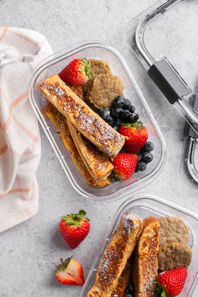 Protein french toast sticks with fruit and turkey sausage in meal prep containers