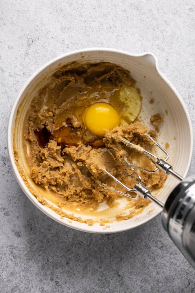 Egg and vanilla being mixed in with an electric mixer.