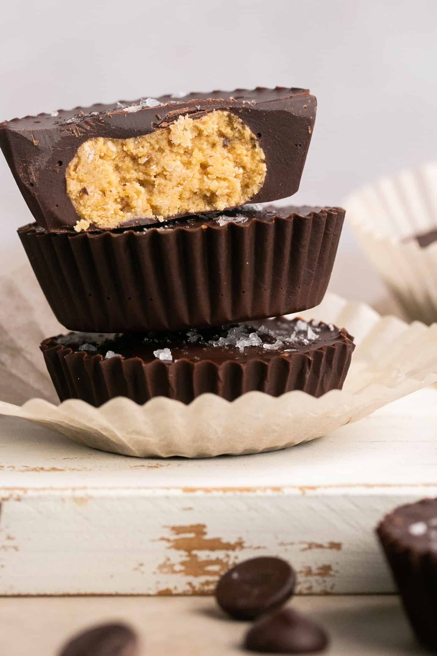 Healthy chocolate cookie dough cups stacked on top of each other on a small plate.