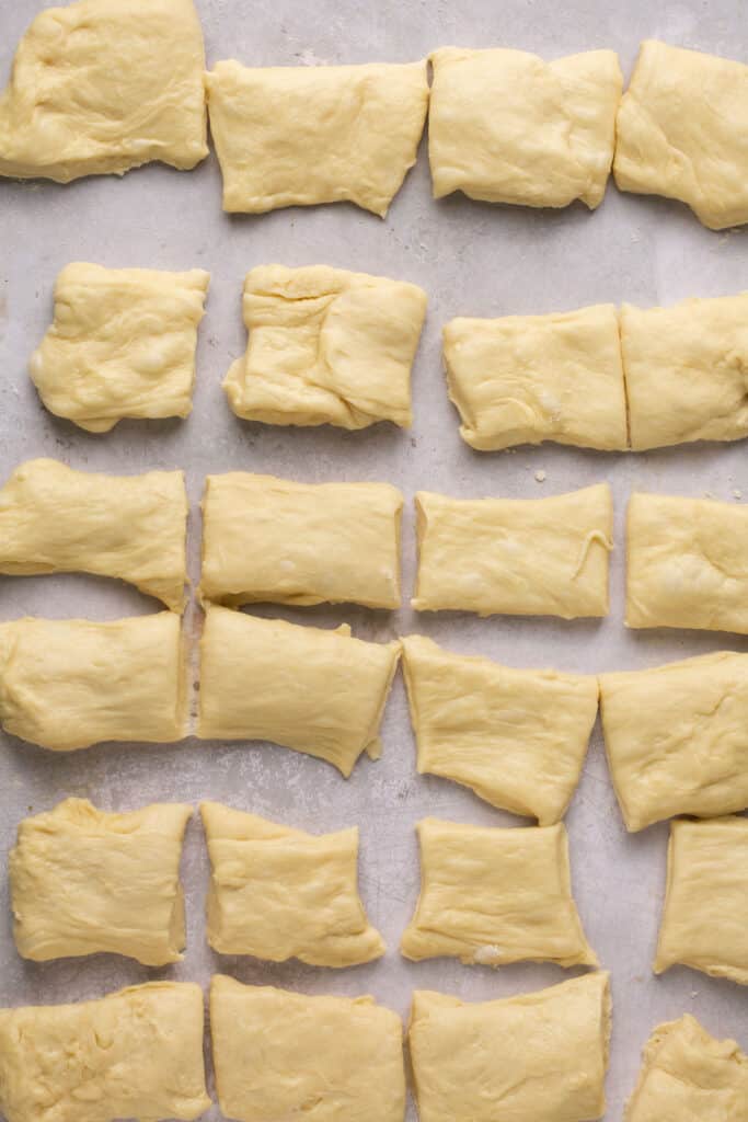 Dough for honey butter yeast rolls shaped into rectangles on parchment paper.