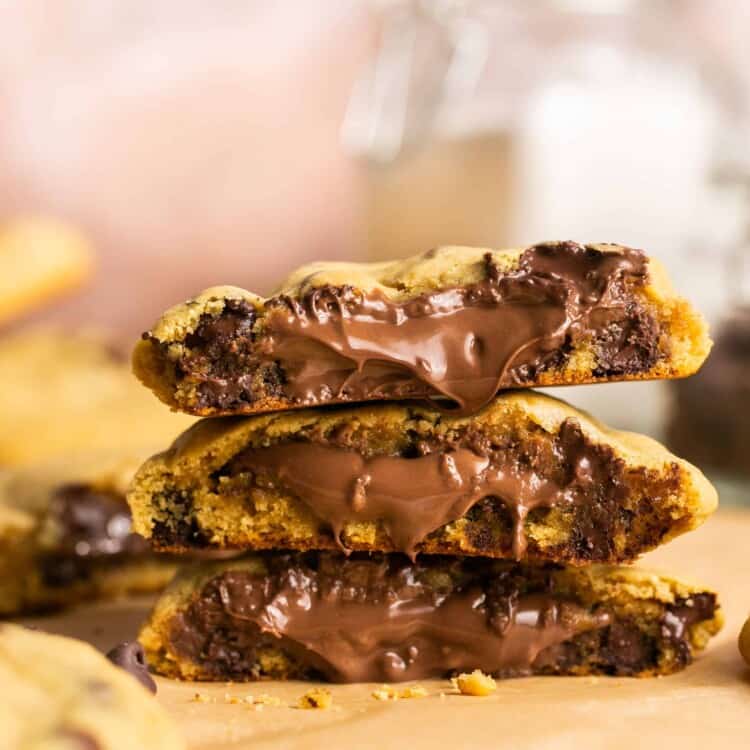 Nutella stuffed chocolate chip cookies broken in half and stacked on top of each other.