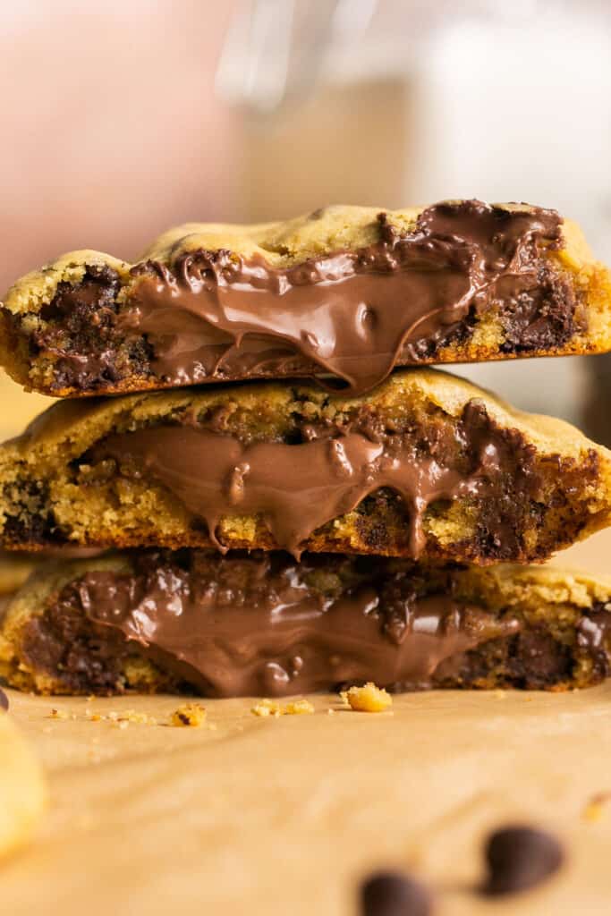Giant Nutella Chocolate Chip Cookies with gooey filling broken in half and stacked vertically