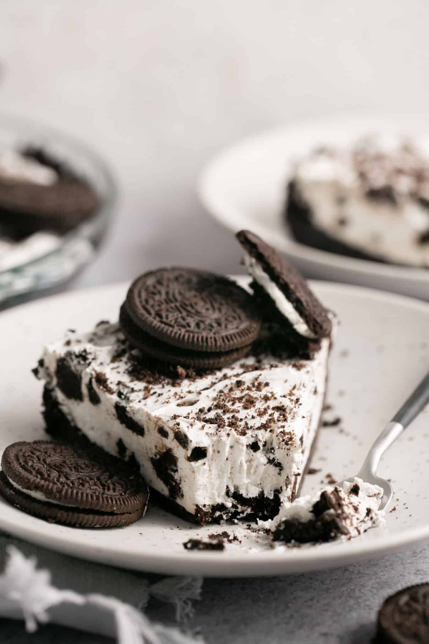 A slice of No Bake Oreo Pie with Cool Whip on a white plate.