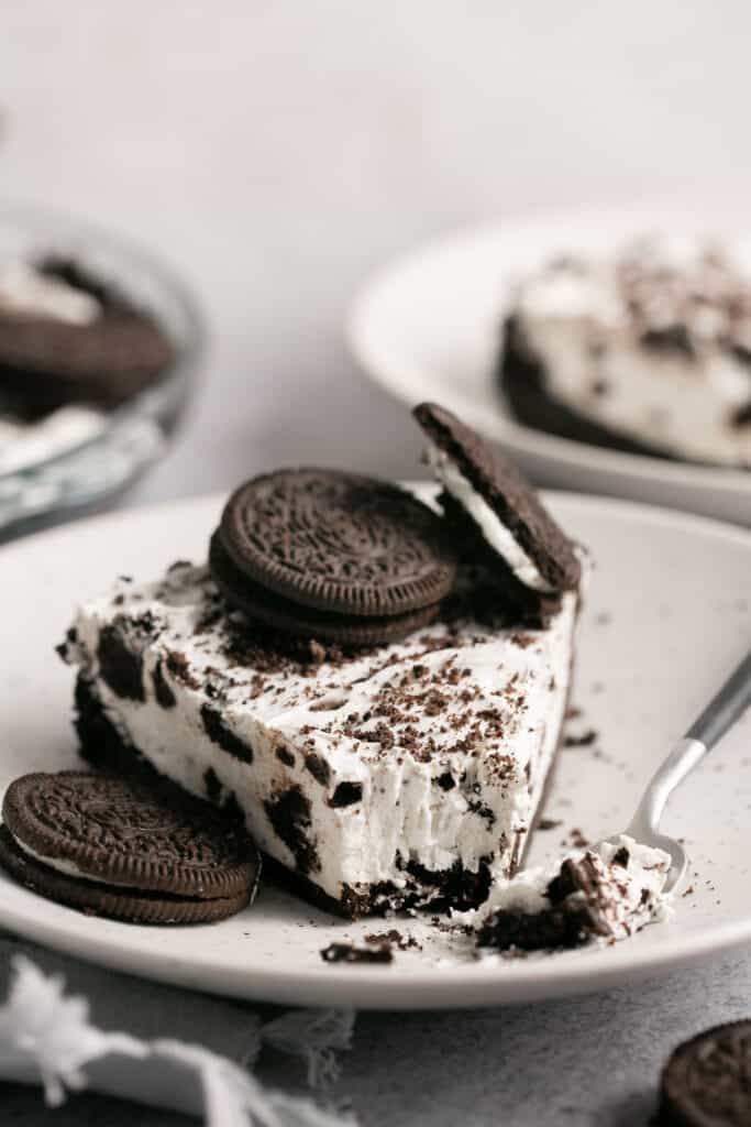 A slice of no bake oreo pie on a plate topped with additional oreos