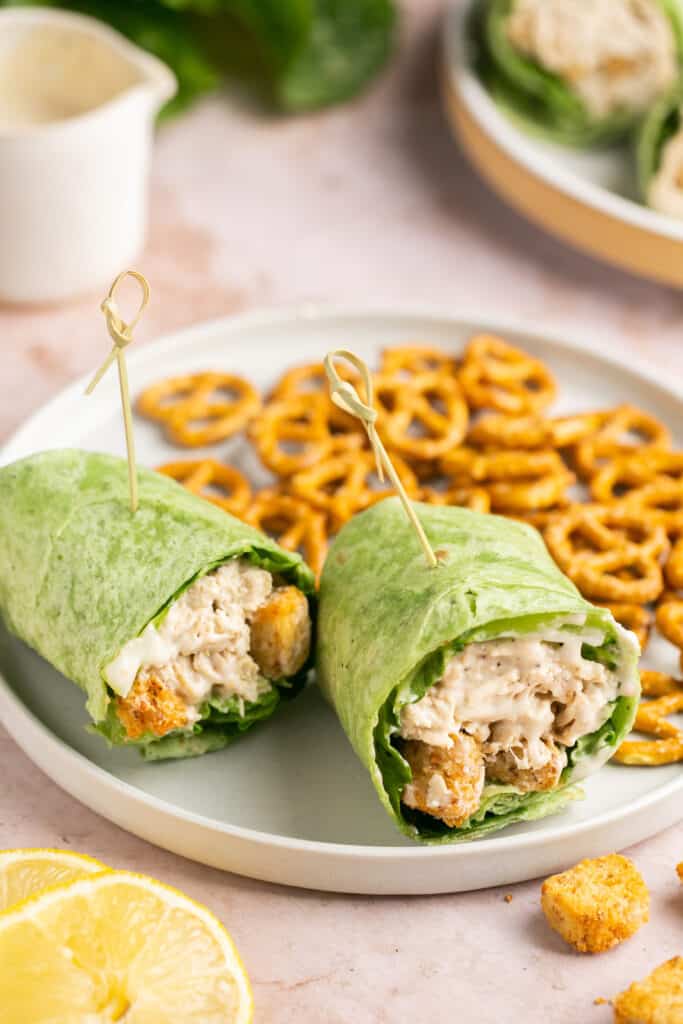 Chicken Caesar Wrap cut in half served on a plate with a side of pretzels
