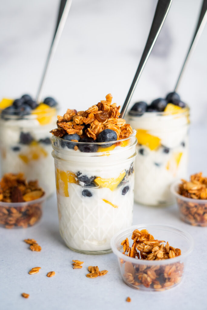 Greek yogurt parfaits with granola and fruit in mason jars with spoons