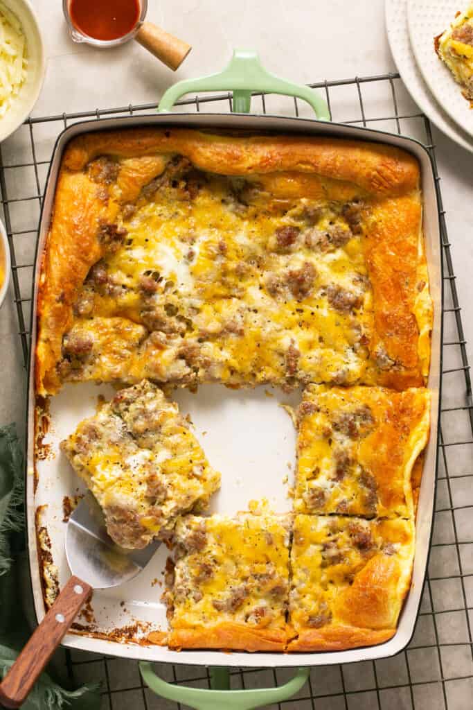 Crescent Roll Breakfast Casserole in a baking dish, some cut into squares and being served with a metal spatula