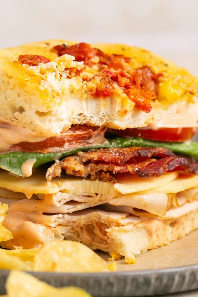 Zoomed in view of Panera bacon turkey bravo on a plate with chips.