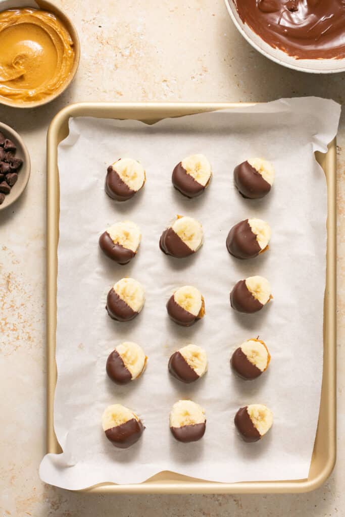 Chocolate Peanut Butter Banana Bites on a baking sheet with parchment paper.