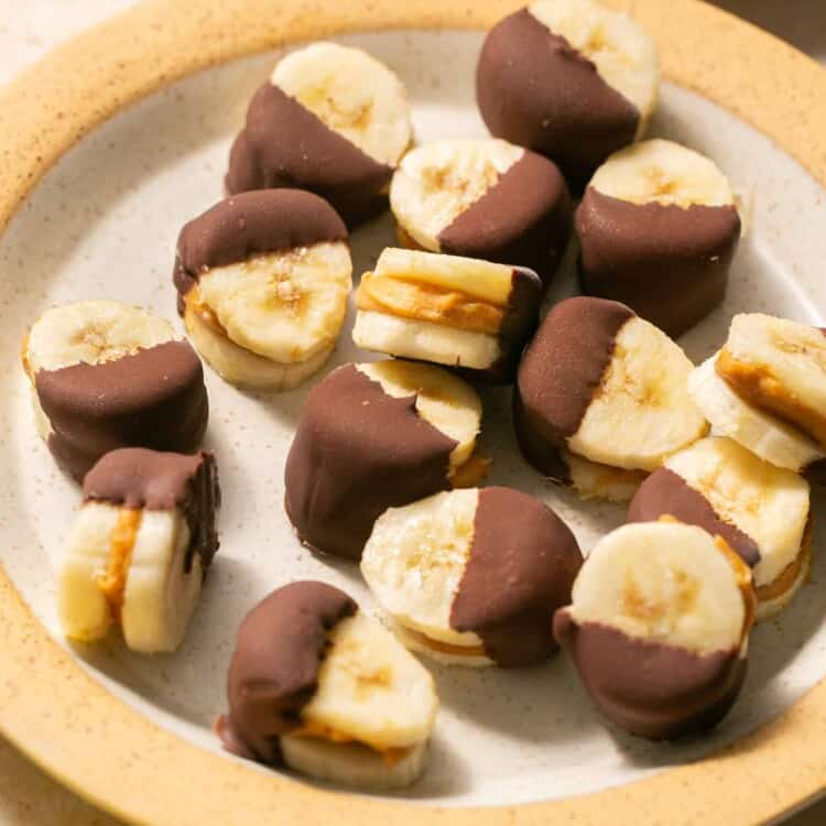 Peanut butter banana bites dipped in chocoalte on a plate.