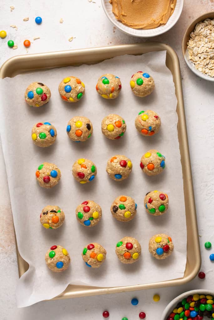 Monster cookie low calorie protein balls on a baking sheet with parchment paper.