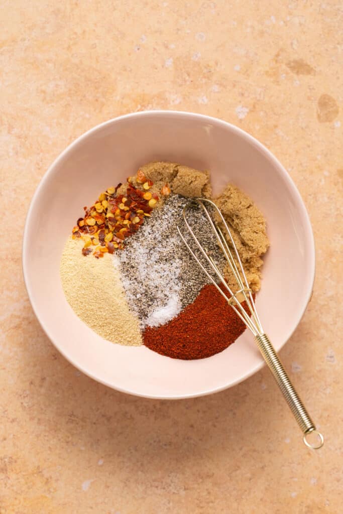 Spices in a small bowl with a whisk.