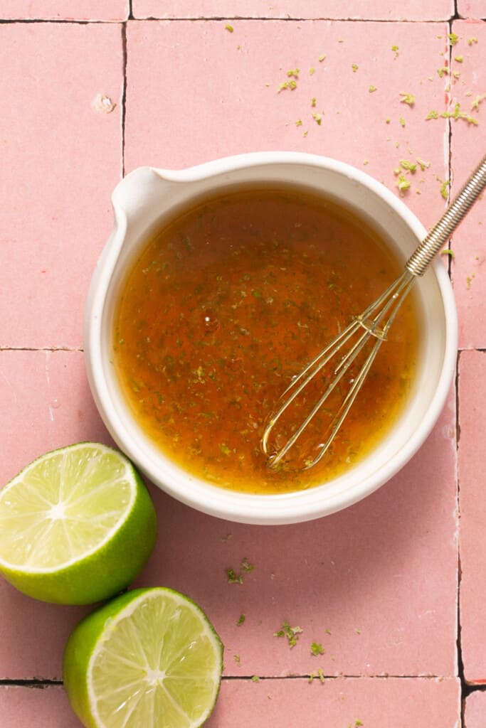 Honey lime dressing in a bowl with a whisk