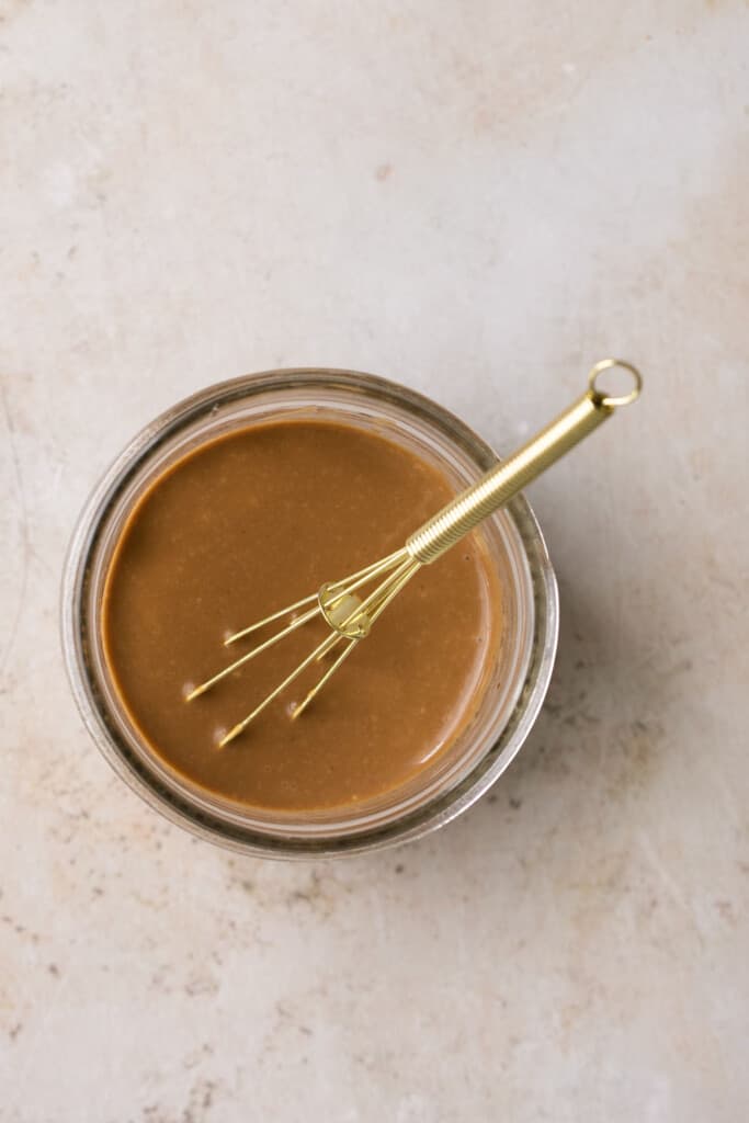 Creamy balsamic dressing in a jar with a whisk