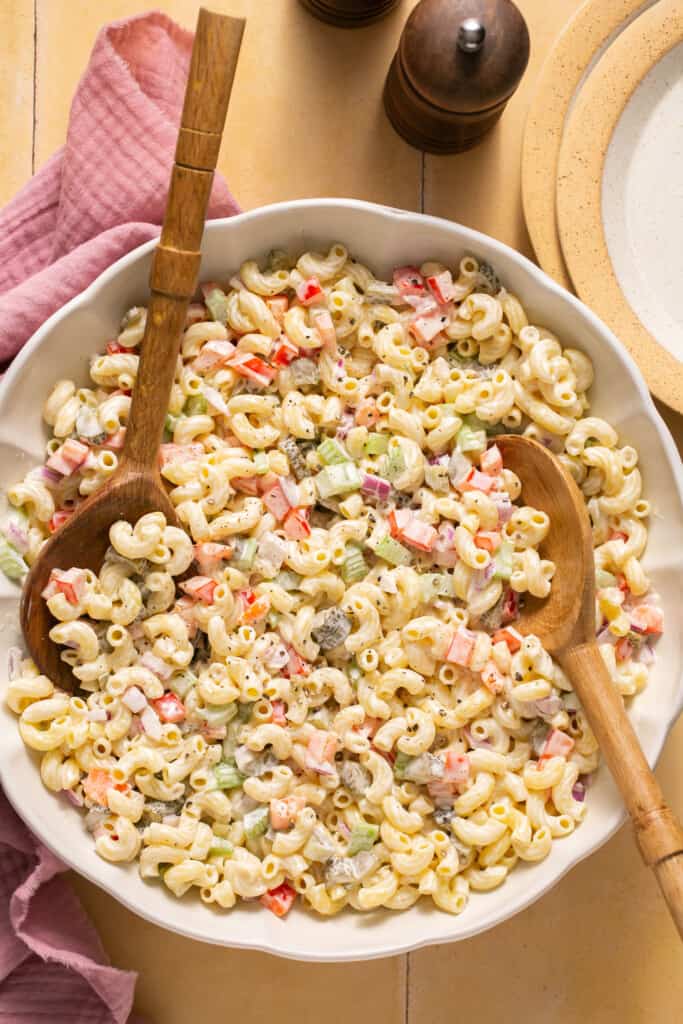 Healthy macaroni salad (deli style) in a large bowl with a wooden spoon.